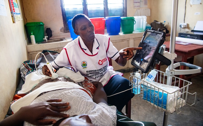 Nurse Beth Marete conducts an ultrasound scan with handheld ultrasound device on patient, Chiza Wabungo, at the Shangia Dispensary in Mariakani, Kenya on May 16, 2023.